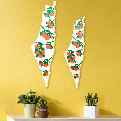 Two decorative wall art pieces shaped like palestine with fruit design on a yellow wall.