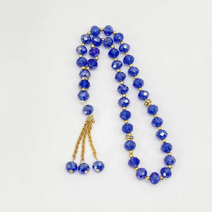 Blue prayer beads with gold accents on a white background