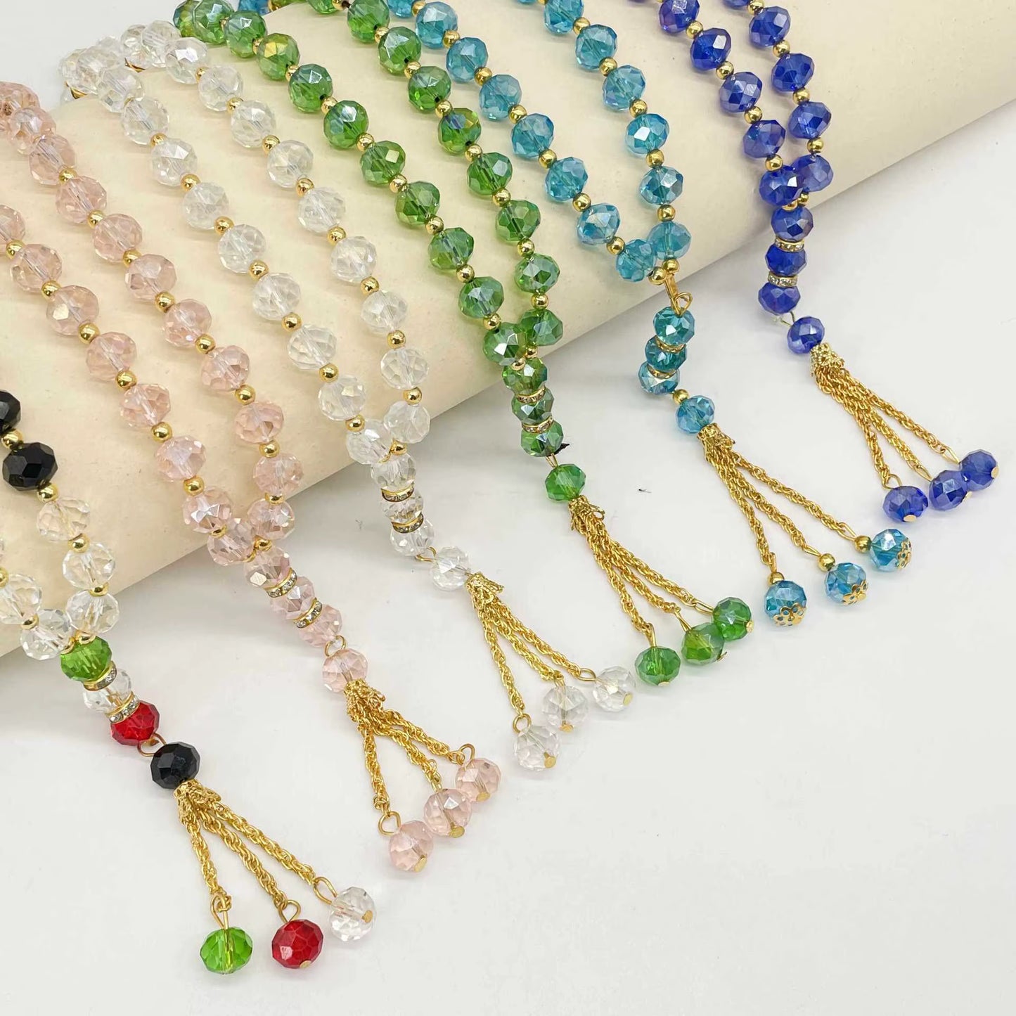 Colorful beaded prayer beads with tassels on a white surface