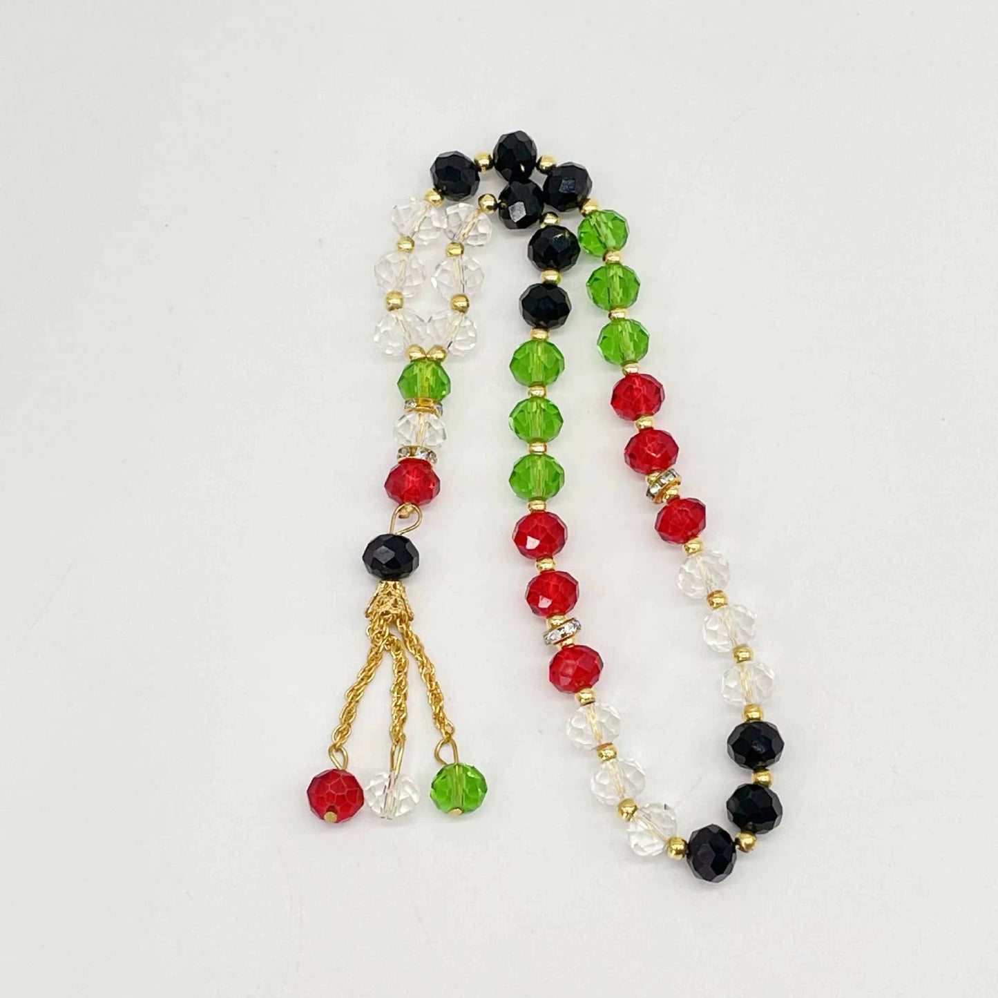 Beaded prayer beads with red, green, and black beads on a white background