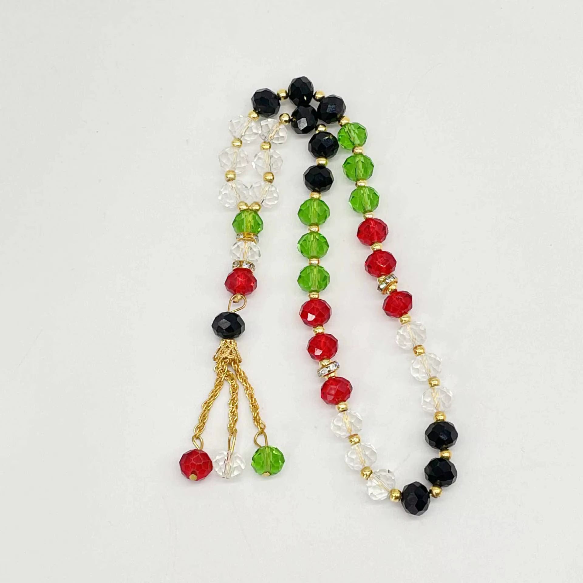 Beaded prayer beads with red, green, and black beads on a white background