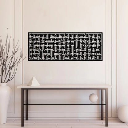 Black geometric patterned Islamic wall art kufic calligraphy of Ayatul Kursi on a white wall above a glass table.