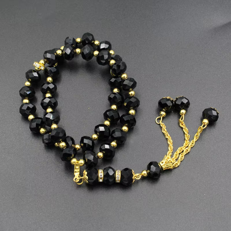Black beaded prayer beads with gold accents on a gray background