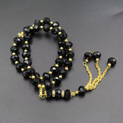 Black beaded prayer beads with gold accents on a gray background
