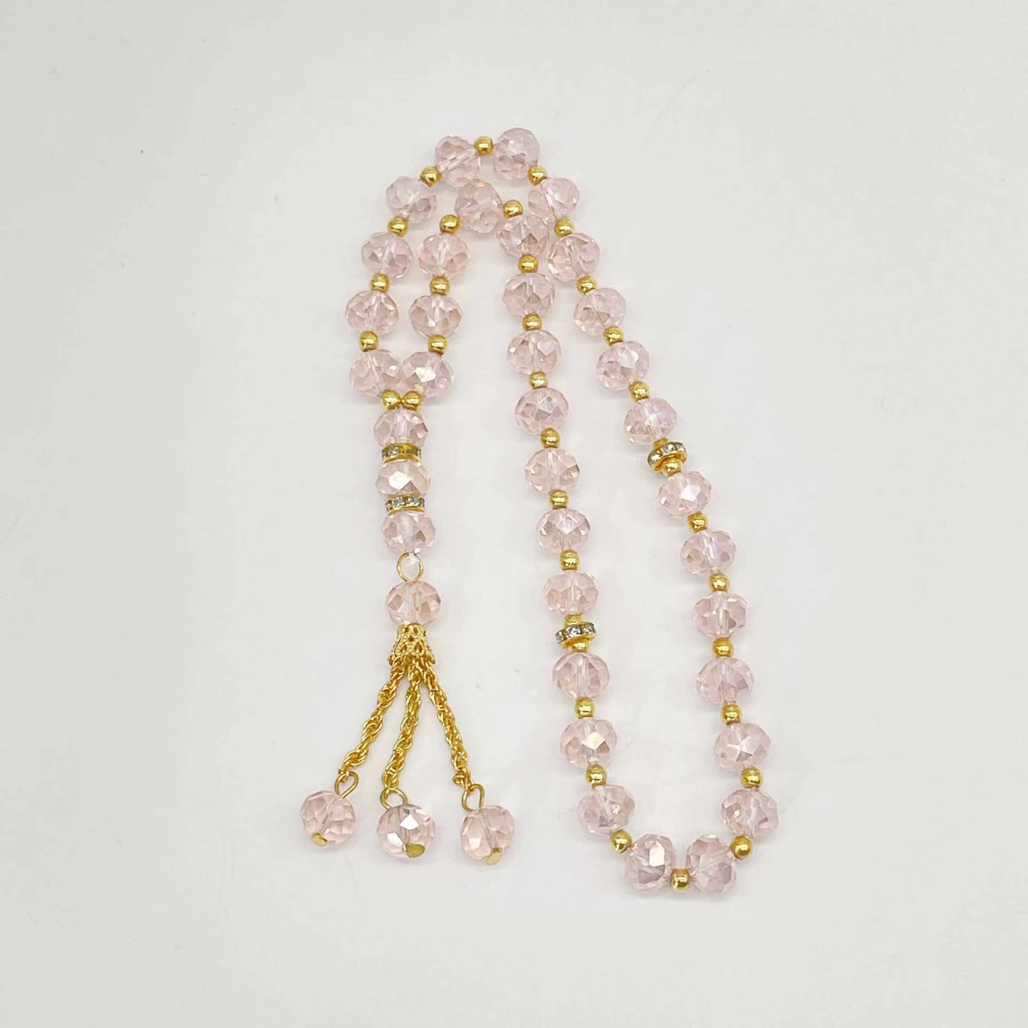 prayer beads with pink beads and gold accents on a white background