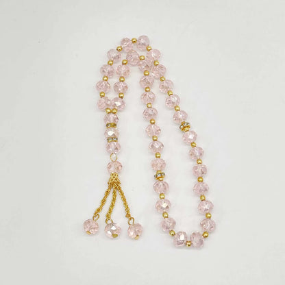 prayer beads with pink beads and gold accents on a white background