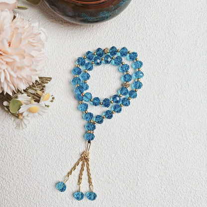 Blue beaded prayer beads with gold accents on a light background