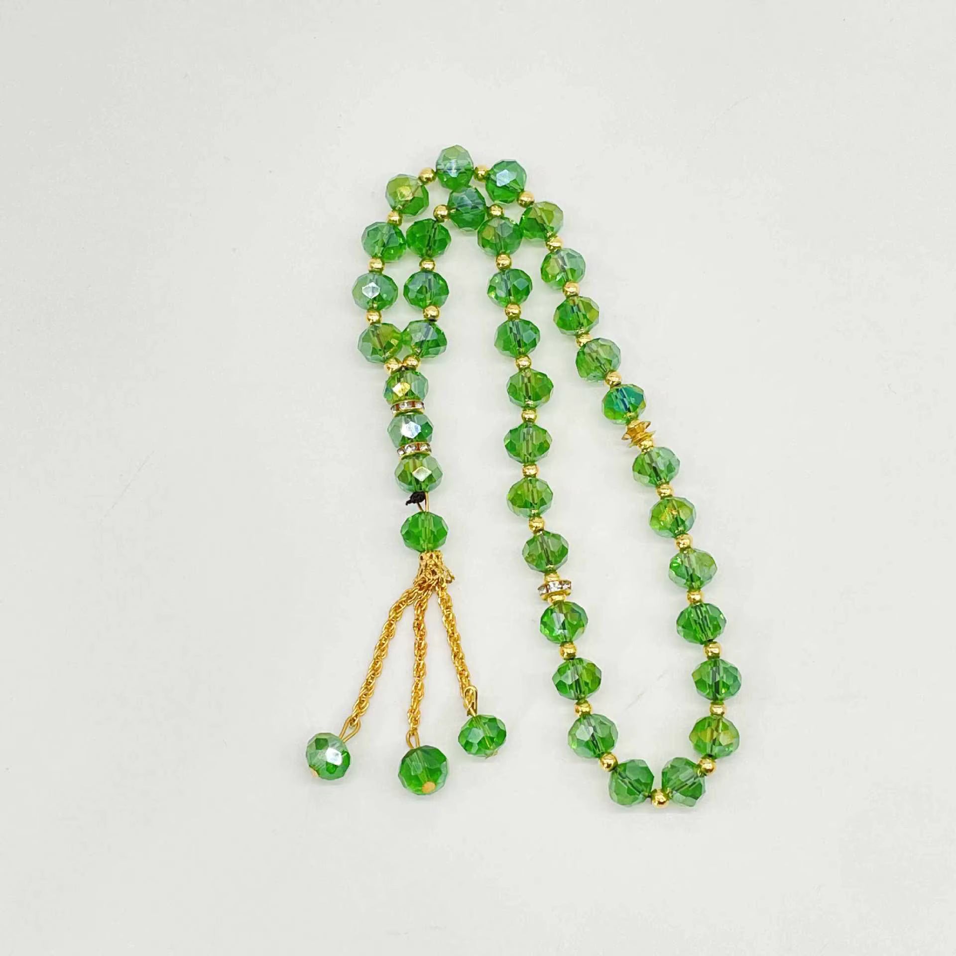 Green beaded prayer beads with gold accents on a light gray background